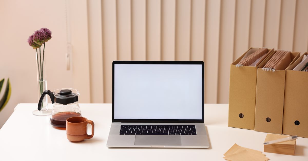 A minimalist workspace featuring a laptop, folder organizers, and coffee, ideal for productivity.